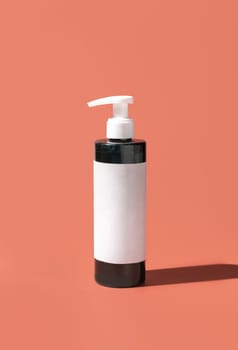 Cosmetic One pump Plastic bottle with blank label on pink, hard shadows, close up, mockup. Skincare beauty product, facial cleaner or lotion. Natural cosmetics..