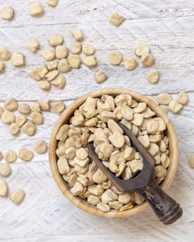 Bowl of raw dry Grass pea on wood top view. Healthy, protein source for vegan and vegetarian diet. Traditional Italian apulian cuisine ingredient. Legumes known as Cicerchia, Vetch, Blue Sweet Pea
