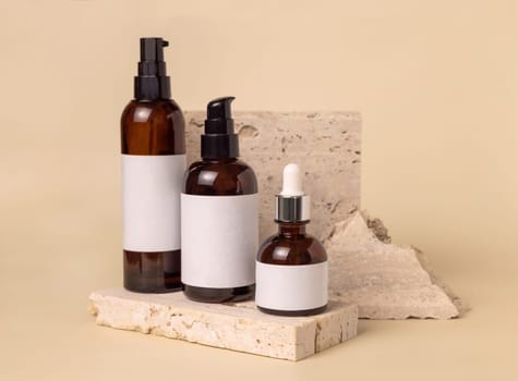 Brown glass one pump bottles on travertine stones on light beige close up, label mockup. Skincare beauty product package. Natural cosmetics, minimal composition..
