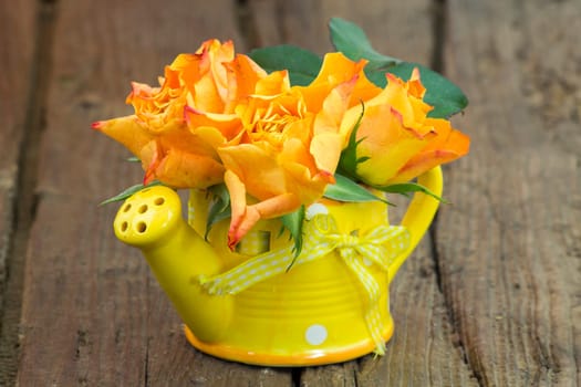 orange roses in a vase - wooden background