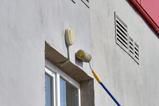painting the street wall with a roller with gray paint. High quality photo