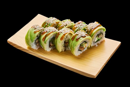The Green Dragon roll is laid out on a wooden stand on a black isolated background. High quality photo