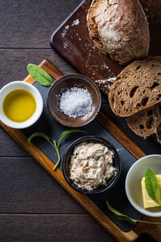 Spelt bread with homemade tuna spread, olive oil and salt on wooden background