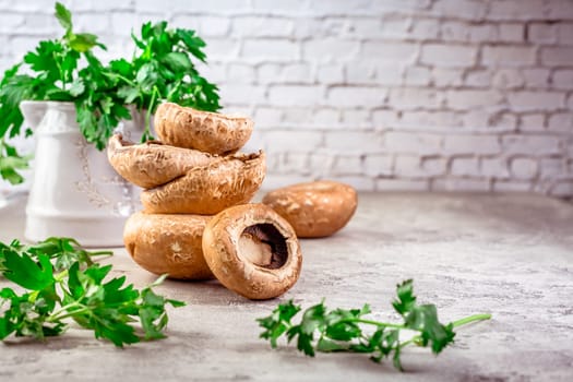 Raw portobello mushrooms with fresh parsley on kitchen table prepared for cooking