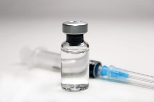 Syringe and a bottle of medicine close-up on a light background. Blurred background.