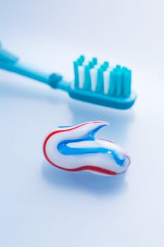 Colorful toothpaste and toothbrush on blue background, concept of dental care and hygiene