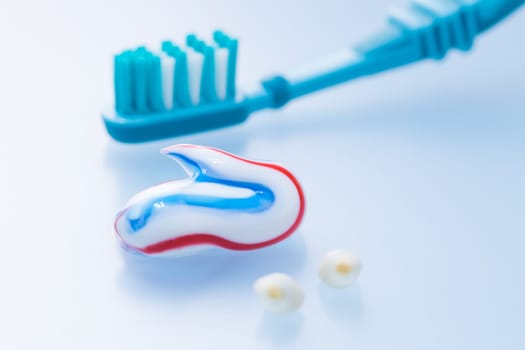 Colorful toothpaste and toothbrush with primary teeth on blue background, concept of dental care and hygiene