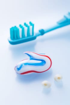 Colorful toothpaste and toothbrush with primary teeth on blue background, concept of dental care and hygiene