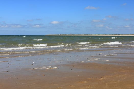 Waves with whitecaps flood the sandy beach.Wellen mit weißen Schaumkronen überfluten den Sandstrand .