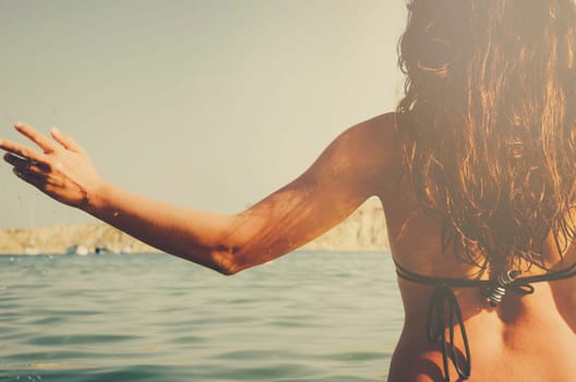 Young hipster girl from behind having fun in the sea. Summer holiday travel to tropical island.