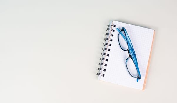 Empty notebook and eyeglasses on a gray background, brainstorming for new ideas, writing a message, home office desk, template of a workspace, copy space for text