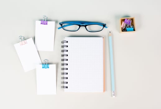 Blank notebook with a pen, paper and eyeglasses on a gray background, brainstorming for ideas, writing a message, workplace desk, home office