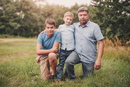 Father with his sons standing in the natural park. Concept of family relation and love.