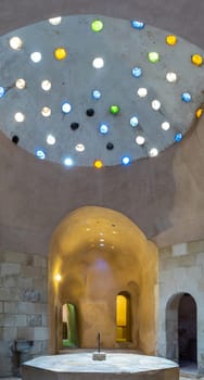 Arched stone wall lighted by colored circular shaped roof holes at a historical traditional Turkish style bath named Hamam Inal, Medieval Cairo, Egypt