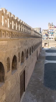 Stone bricks old weathered fence with wooden doors, arched stucco window, and floral engraved decorations, Ibn Tulun mosque, Sayyida Zaynab district, Medieval Cairo, Egypt