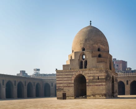 Courtyard of Ibn Tulun public historical mosque with ablution fountain and arched passages surrounding the courtyard in the background, Sayyida Zaynab district, Medieval Cairo, Egypt