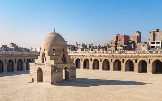 Courtyard of Ibn Tulun public historical mosque with ablution fountain and arched passages surrounding the courtyard in the background, Sayyida Zaynab district, Medieval Cairo, Egypt