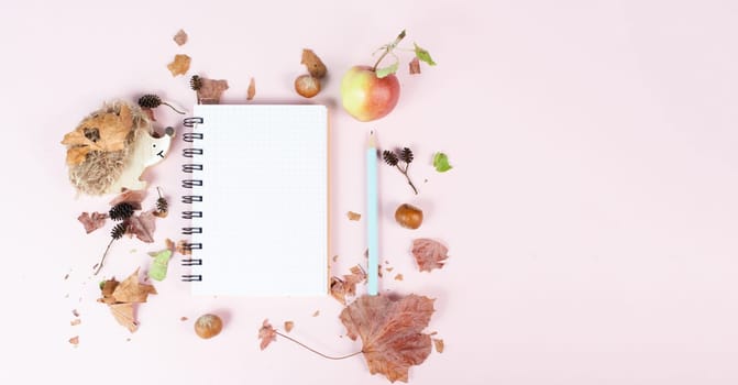 Empty notebook with an apple and a hedgehog, autumn background with colorful leaves, office desk, pastel color