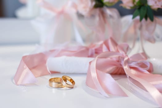 Wedding details, symbol of love and marriage. Close up of gold universal wedding rings lying on the table. Concept of wedding symbols and attributes.