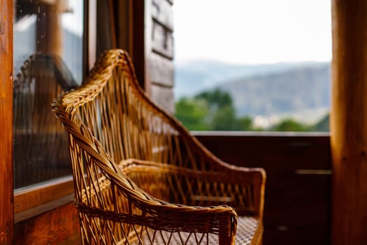 Close up of wicker bench on the balcony of a wooden cottage with amazing mountain views. Selective focus. Good places to relax with a natural view.