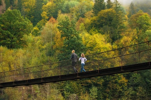 Morning sports run. Couple of athletes in the morning jogging on a suspension bridge on a background of green mountain forest. Jogging, active lifestyle concept.