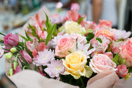 Composition from flowers. Close up of a festive bouquet of fresh flowers made in pink. Roses, astrumeria and chrysanthemums in one bouquet. Concept of giving flowers for a birthday or wedding.