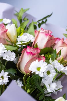 Close up of roses and chrysanthemums stacked in a festive bouquet. Flower arrangement with pink roses, white chrysanthemums and sprigs of greenery. Concept of Women's Day, Mother's Day and Birthday.