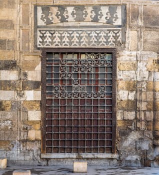 Wooden grunge window with decorated iron grid over stone bricks wall, Moez Street, Cairo, Egypt