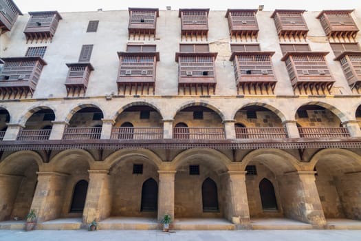 Facade of historic Wikala of Bazaraa building, with vaulted arcades and oriental wooden oriel windows, suited in Tombakshia street, Gamalia district, Medieval Cairo, Egypt