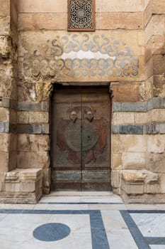 Wooden decorated copper plated door and stone bricks wall leading to Sultan Barquq mosque, Al-Moez Street, Old Cairo, Egypt