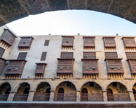 Facade of historic Wikala of Bazaraa building through stone arch , with vaulted arcades and oriental wooden oriel windows, suited in Tombakshia street, Gamalia district, Medieval Cairo, Egypt