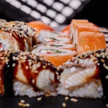Close up roll of Philadelphia with cream cheese, salmon, cucumber and caviar lies among delicious nigiri sushi. Selective focus. Blurred background.