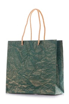 Close up of blank dark green nacre gift bag with raised handles. Package is made of crepe paper. Consumer pack ready for logo design. Isolated on a white background.