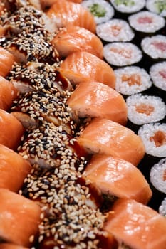 Food background. Large set with rows of different types of sushi rolls with different fillings. Japanese traditional cuisine.