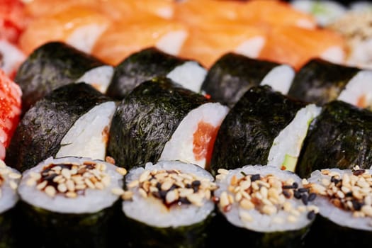 Close up of roll with salmon and sesame seeds wrapped in nori leaves. Japanese oriental cuisine.