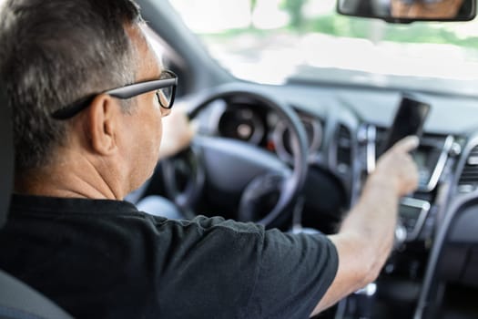 Senior behind the steering wheel using navigation and looking for directions