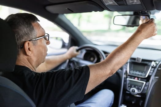 Happy senior in his 70s driving a car