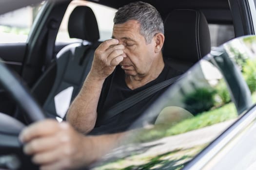Tired pensioner in his 70s, dring in a car
