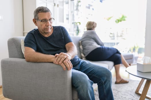 Upset senior couple at home in living room having an argument