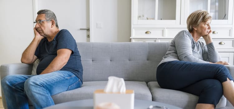 Upset senior couple at home in living room having an argument