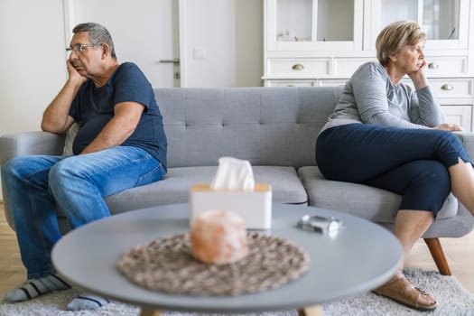 Upset senior couple at home in living room having an argument