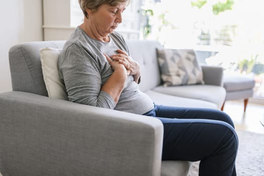 Elderly woman at home with heart pain holding her chest