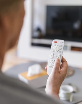 Senior woman with remote control watching television
