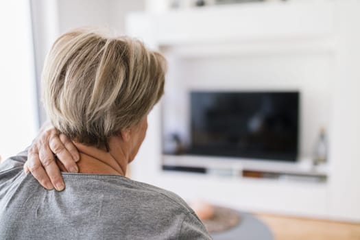 Senior woman in the living room with neck pain