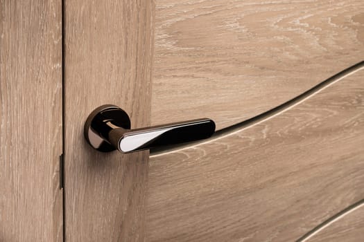 External door handle without protective lock on wooden frame. Close up of metallic door handle on brown front or interior door. Home door design choice concept.