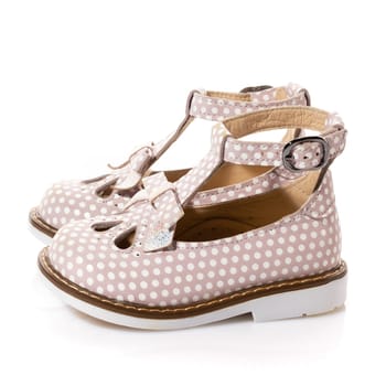 Side view of children's summer sandals for girl isolated on white background. Close up of cute soft pink baby shoes with white dots. Children's fashion concept.