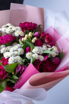 Close up of a bouquet of pink and white flowers wrapped in floral tracing paper. Concept of floristics and composing greeting bouquets. Floral banner.