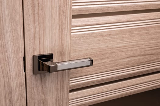 External door handle without protective lock on wooden frame. Close up of metallic door handle on brown front or interior door. Home door design choice concept.