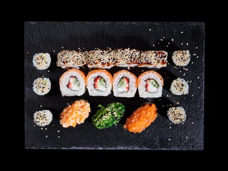 Top view various kinds of sushi served on a dark background. Asian food fest. Menu sushi with nigiri, maki, uramaki on black plate. Japanese restaurant menu.