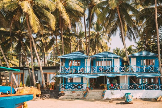 Canacona, Goa, India. Famous Painted Guest Houses On Palolem Beach Against Background Of Tall Palm Trees In Sunny Day.